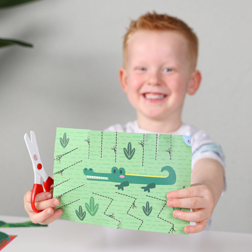 小朋友拿著完成的鱷魚主題剪紙作品(使用SES安全剪刀),很開心。